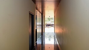 Un pasillo con techo de madera, puertas de cristal y vistas a un espacio exterior.