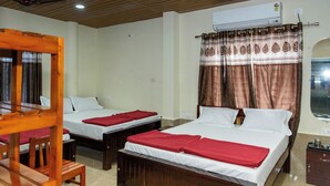 Habitación de hotel con dos camas, muebles de madera, una ventana con cortinas y un equipo de aire acondicionado.