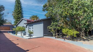 A modern building with a red roof, a brick pathway, and a variety of trees. - Boutique Hotel-Style Room In Ferndale-B2 (Randburg)