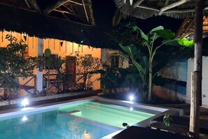 Una piscina al aire libre, sombrillas, sillones reclinables de piscina