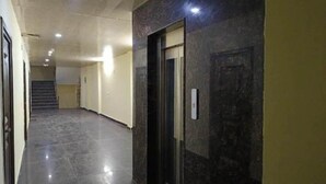 A hallway with a marble wall, a door, and a staircase in the background. - Hotel Royal Residency (New Delhi)