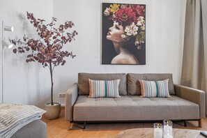 A modern living room with a grey sofa, striped pillows, a potted plant, and a framed artwork on the wall. - LIVU Admiral: 130sqm apartment | an old town dream + roof terrace (Wismar)