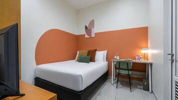 Una habitación de hotel con cama, escritorio con lámpara, televisor y puerta.