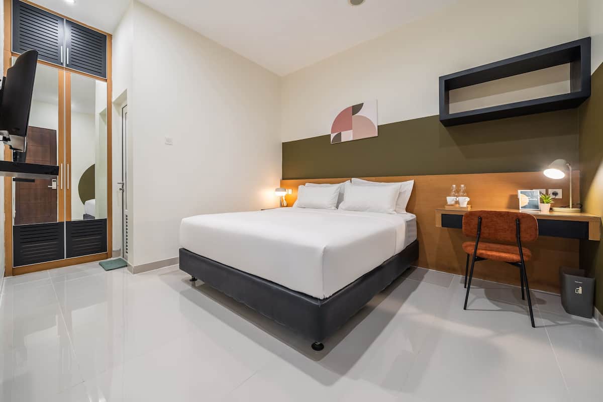 Una habitación de hotel moderna con cama, escritorio, silla y armario.
