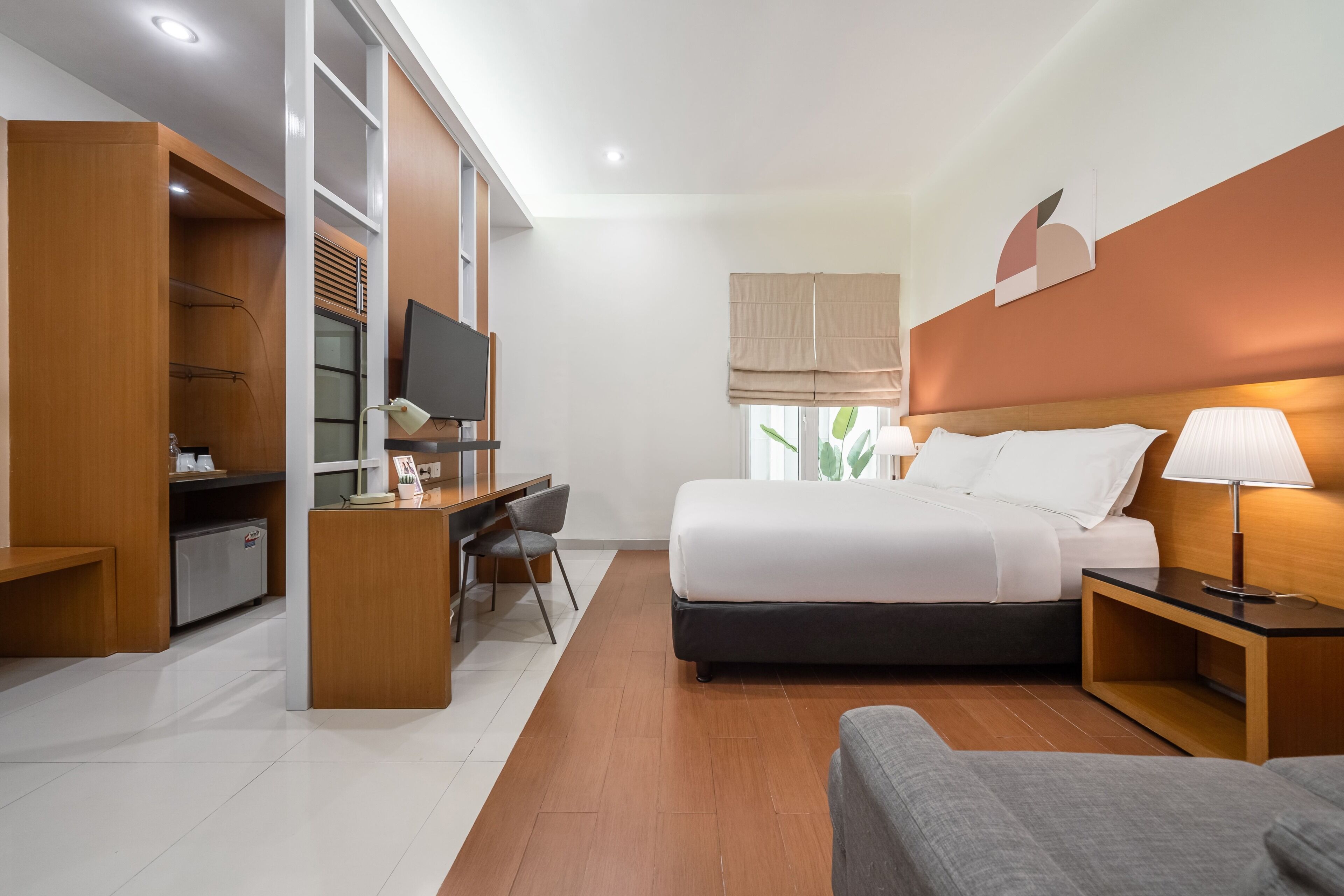 Une chambre d’hôtel équipée d’un lit, d’un bureau, d’une chaise, d’une télévision et d’une fenêtre donnant sur un paysage agréable.