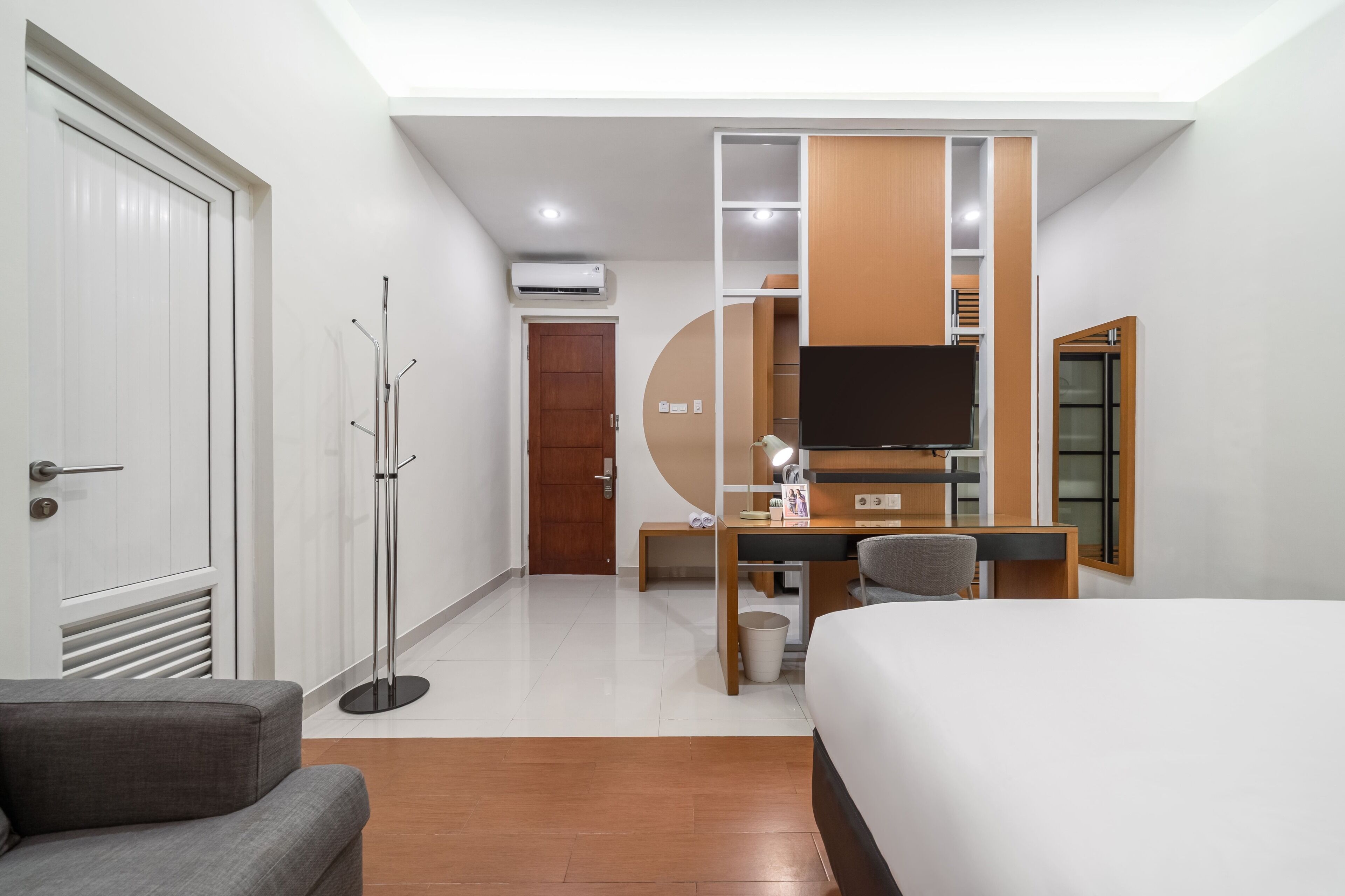 Une chambre d’hôtel comprenant un lit, un bureau avec une chaise, une télévision, un porte-manteau et une armoire.