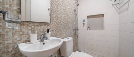 A bathroom with a sink, toilet, and shower.