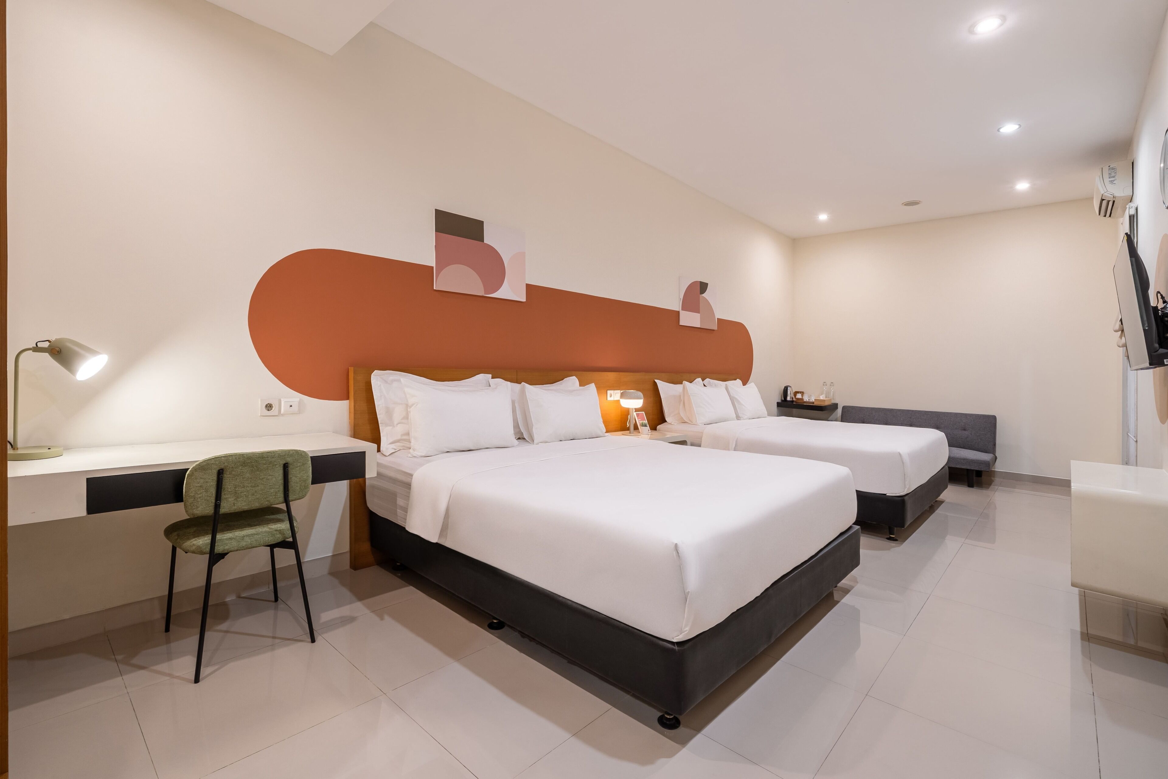 A hotel room with two beds, a desk, a chair, and a large abstract artwork on the wall.