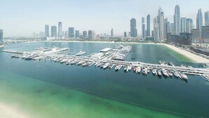 Un puerto deportivo con barcos amarrados, un horizonte urbano al fondo y un cielo despejado.