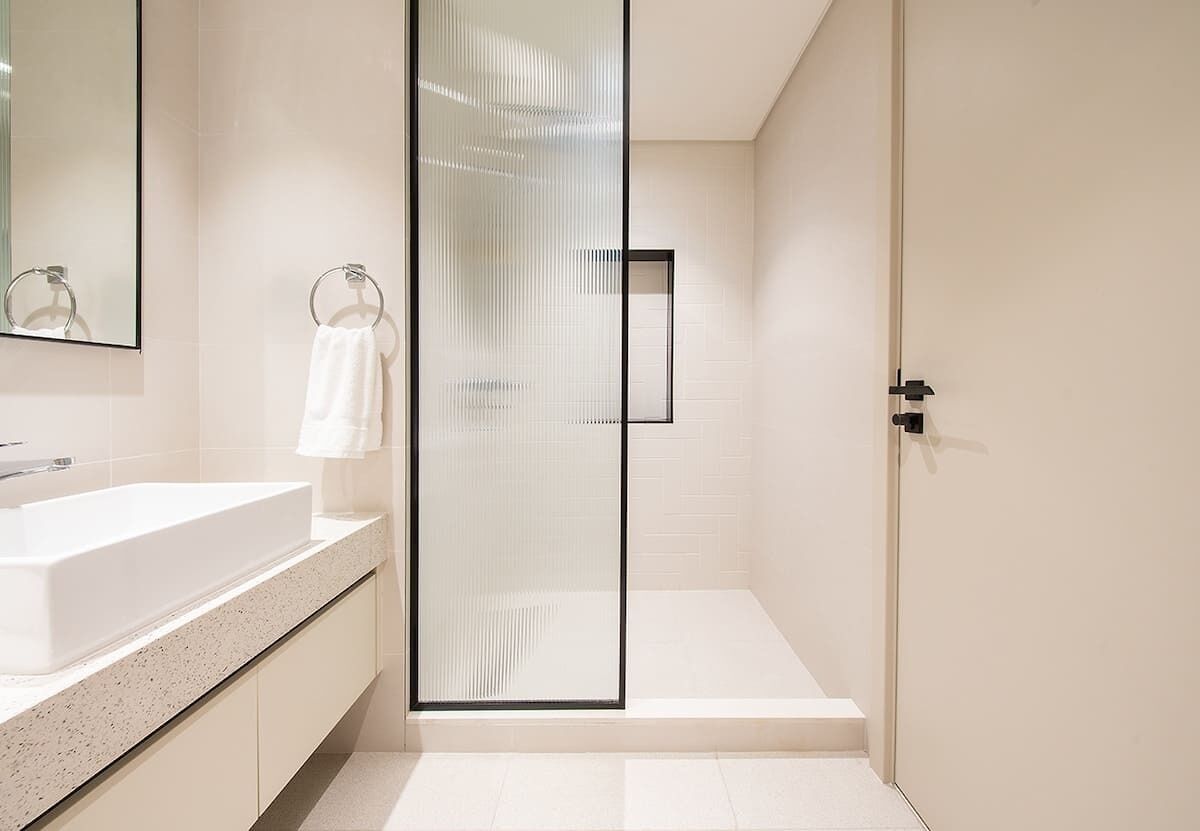 Une salle de bain moderne avec une douche à parois de verre, un lavabo blanc et un porte-serviettes.