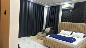 A modern bedroom with a bed, a chair, a small table, and a wall-mounted clock.
