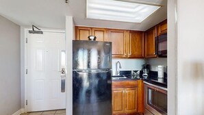 A kitchen with wooden cabinets, a stainless steel refrigerator, a microwave, and a coffee maker. - Oceanfront Balcony | Resort Pools & Lazy River (Myrtle Beach)