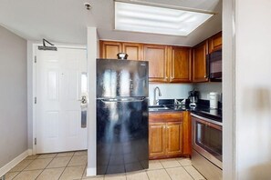 Eine Küche mit Holzschränken, einem Edelstahlkühlschrank, einer Mikrowelle und einer Kaffeemaschine.