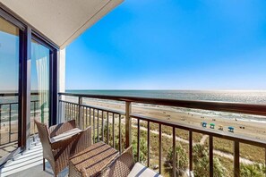 A balcony with wicker furniture overlooking a beach. - Oceanfront Balcony | Resort Pools & Lazy River (Myrtle Beach)