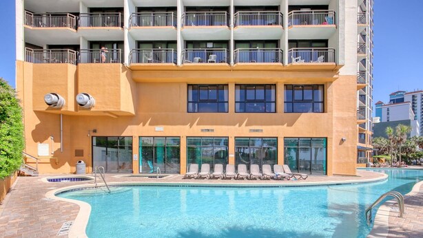Un hotel con piscina, varios balcones y un camino de ladrillo.