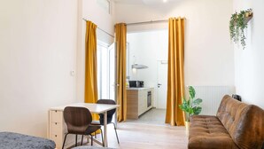 Ein Zimmer mit Bett, Schreibtisch, Sessel, Sofa und Küchenzeile.