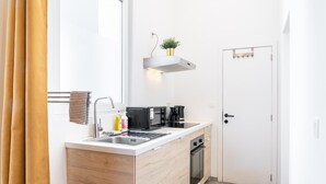 Eine kleine Küche mit Einbauherd, Kaffeemaschine und einem Regal mit einer Pflanze.