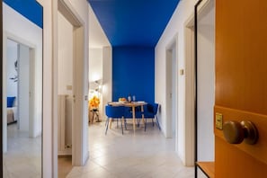 A hallway leading to a dining area with a blue accent wall, a round table with chairs, and a door with a brass handle. - Cozy apartment of 60 sqm, ideal for 4 people, located on the ground floor of a building (with some steps at the entrance).The property is located in a residential area, well served and strategically positioned: just 200 mt from Otranto station, convenien (Otranto)