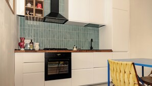 A kitchen with white cabinets, a black oven, a blue tiled backsplash, and a wooden countertop. - Loft Pop-Industrial con vista Acquedotto (Rome)