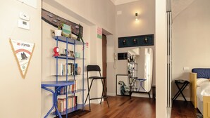 A room with a blue bookshelf, a black chair, a small table, and a bed. - Loft Pop-Industrial con vista Acquedotto (Rome)