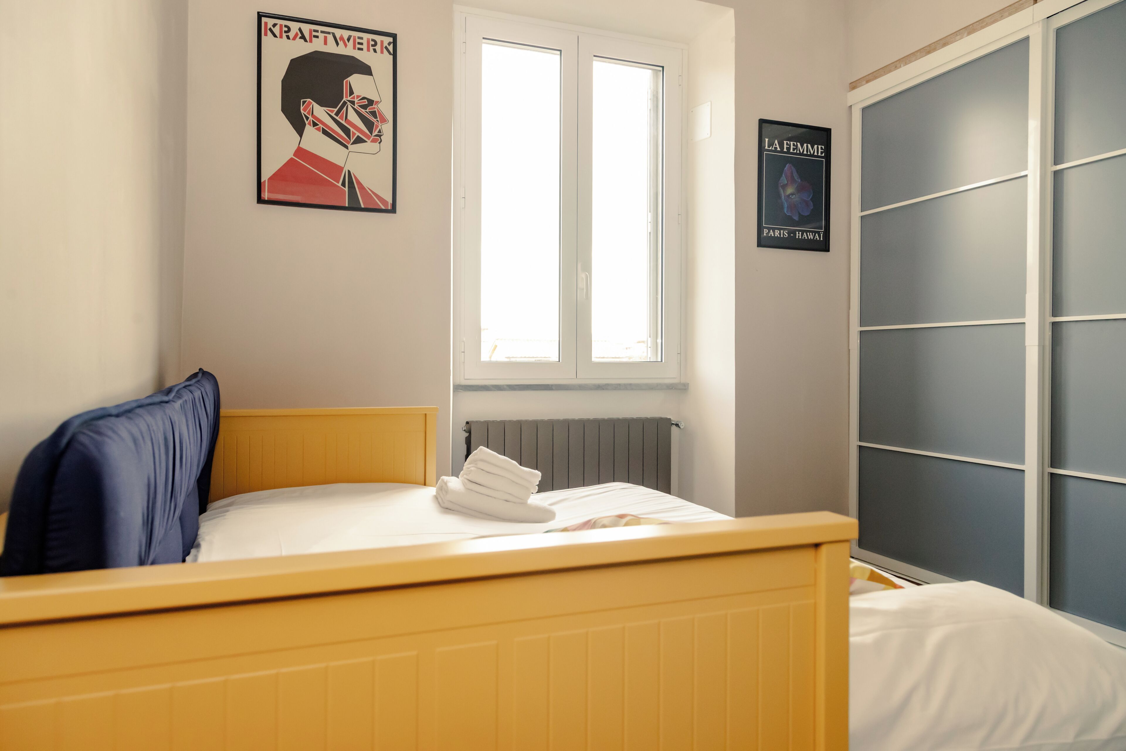 Un dormitorio con cama, ventana, radiador y armario.