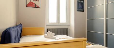 Un dormitorio con cama, ventana, radiador y armario.