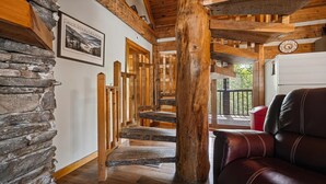 A wooden staircase with stone steps, a leather sofa, and a clock on the wall. - Appalachian Songbird- Charming 2 bedroom cabin & Pet Friendly (Sevierville)