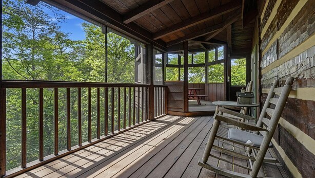 A wooden deck with a railing, a table, and a chair. - Appalachian Songbird- Charming 2 bedroom cabin & Pet Friendly (Sevierville)