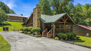 A log cabin-style building with a stone chimney, a porch with stairs, and a picnic table. - American Gem- Charming 2 bedroom cabin all on 1 level & Pet Friendly (Sevierville)