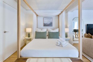 Ein modernes Hotelzimmer mit einem großen Bett, zwei Nachttischen mit Lampen, einem Gemälde an der Wand und einem Fernseher auf der rechten Seite.