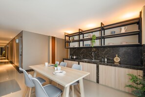 Una cocina moderna con encimera de mármol, armarios de madera y un comedor con una mesa y sillas de color claro.
