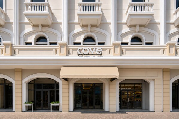 A hotel entrance with a 'COVE' sign, large glass doors, and a covered entrance area.