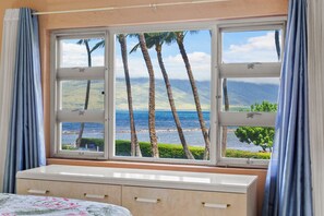A room with a large window, a bed, and a dresser. - Oceanfront Menehune Shores #206, Lanai Views, Pool, Steps to Beach, Relax in Kihei (Kihei, Maui)
