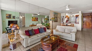 A living room with two white sofas, a glass coffee table, and a ceiling fan. - Oceanfront Menehune Shores #206, Lanai Views, Pool, Steps to Beach, Relax in Kihei (Kihei, Maui)