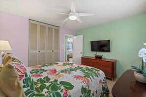 A bedroom with a bed, a dresser, a television, and a ceiling fan. - Oceanfront Menehune Shores #206, Lanai Views, Pool, Steps to Beach, Relax in Kihei (Kihei, Maui)