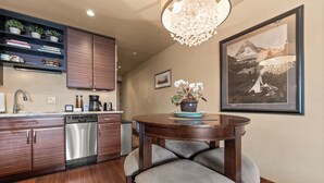 Une cuisine moderne avec des meubles en bois, un lave-vaisselle et un coin repas comprenant une table ronde et des chaises.