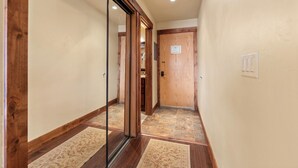 Un couloir doté d’un plancher en bois, d’un miroir et d’une porte donnant sur une autre pièce.