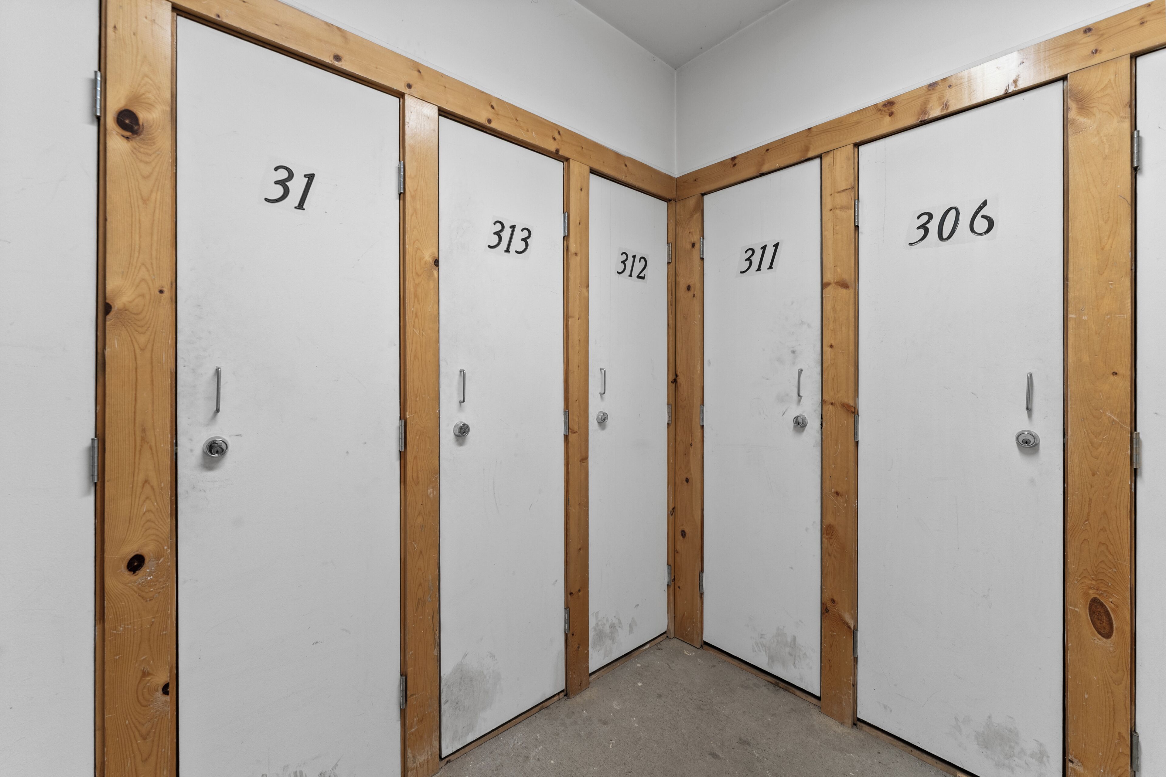 A row of four white doors with numbers 31, 313, 312, 311, and 306, each with a wooden frame and a metal handle.
