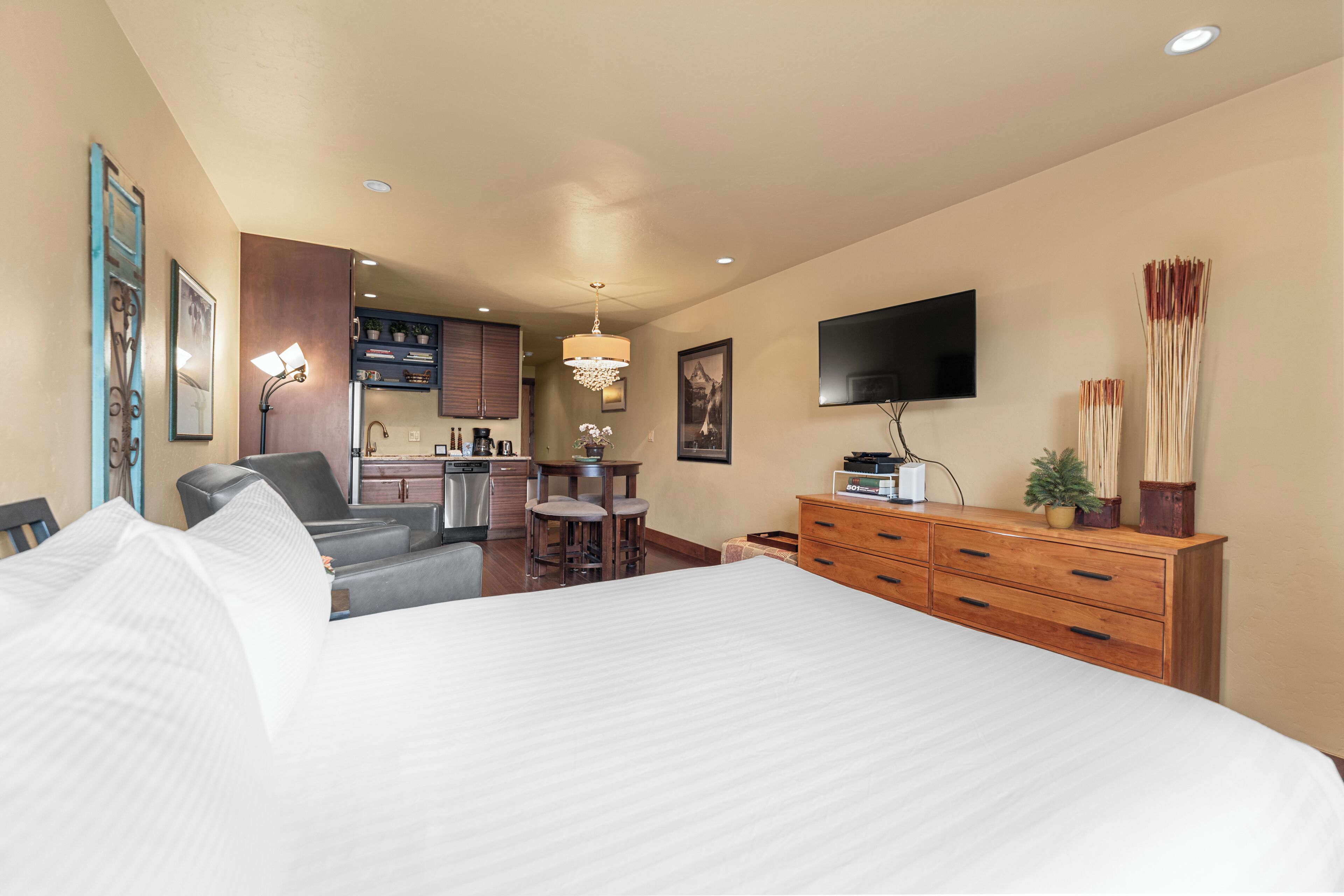 Ein Hotelzimmer mit einem großen Bett, einem Schreibtisch, einem Stuhl, einem Fernseher und einer Holzkommode.