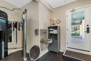 Une salle de sport équipée de matériel d’exercice, d’un distributeur d’eau et d’une horloge au mur.