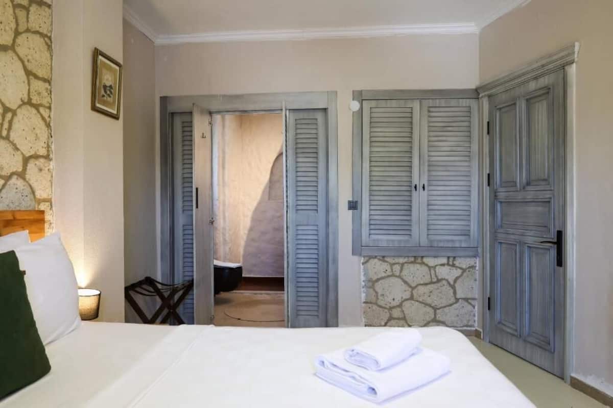 A hotel room with a bed, a chair, a table, and a wardrobe.