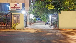 A gated entrance to a building with a sign in a foreign language, a paved pathway, and a parked motorcycle.