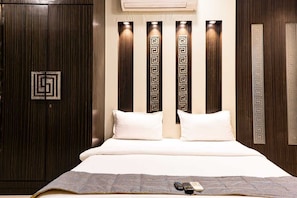 A bedroom with a bed, pillows, a blanket, and a remote control on the bed. - Mumbai Corporate Apartments (Mumbai)