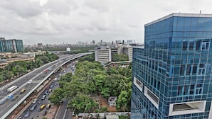 A multi-level highway with vehicles, surrounded by urban buildings and greenery.