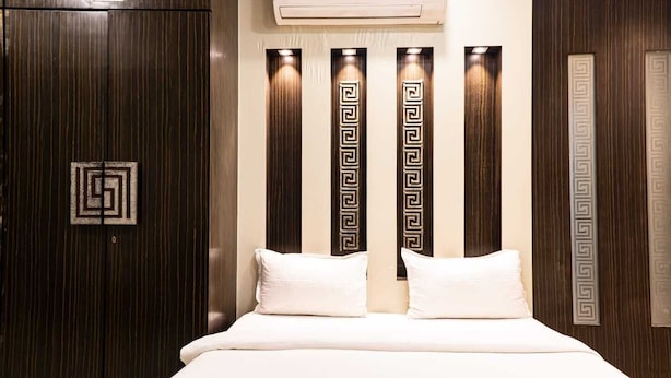A bedroom with a bed, pillows, a blanket, and a remote control on the bed.