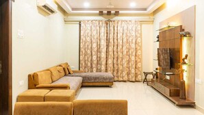 A living room with a sofa, ottoman, TV, and a cabinet.