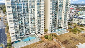 A high-rise hotel with multiple balconies, a swimming pool, and a view of the surrounding area. - Oceanfront l 16th Floor l 4BR l Pool and Lazy River (North Myrtle Beach)