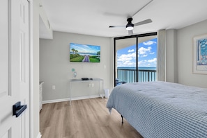 Un dormitorio con cama, televisión, escritorio y balcón con vistas.