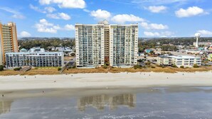 A beachfront hotel with multiple high-rise buildings, a sandy beach, and a clear sky. - Oceanfront l 16th Floor l 4BR l Pool and Lazy River (North Myrtle Beach)