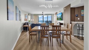 A modern living room with a dining area, large windows, and a view of the ocean. - Oceanfront l 16th Floor l 4BR l Pool and Lazy River (North Myrtle Beach)